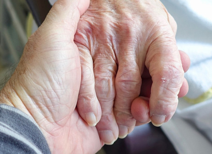 Eine Person hält die Hand einer älteren Person